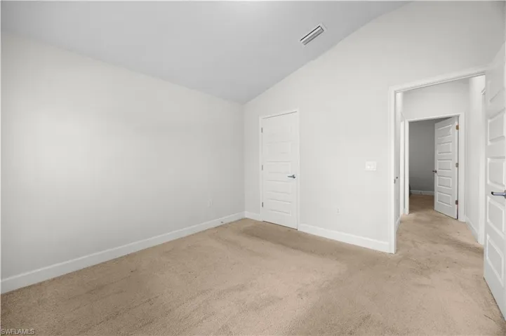 Unfurnished bedroom featuring lofted ceiling and carpet