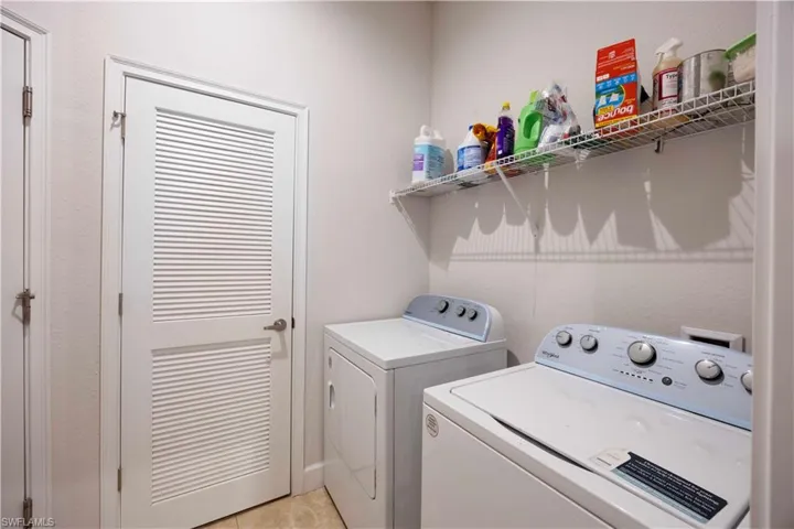 Washroom with washer and dryer and light tile patterned floors