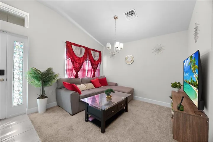 Carpeted living room featuring a chandelier and vaulted ceiling