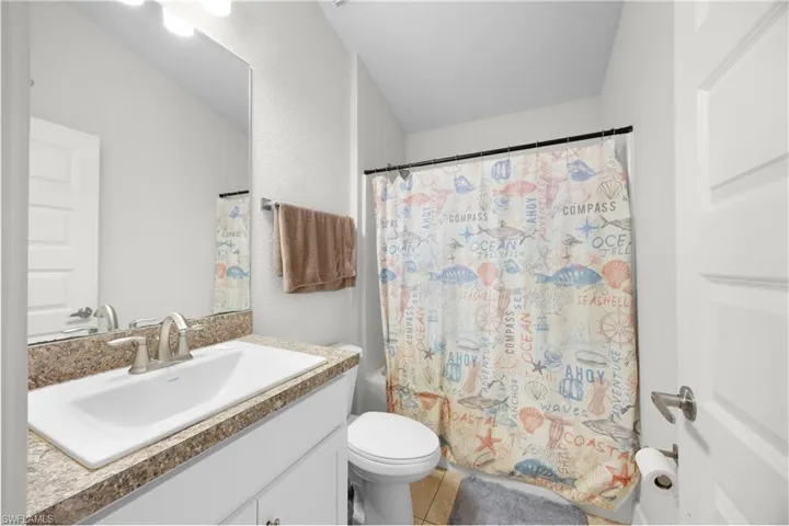 Bathroom with vanity, shower / bath combo, and light tile patterned floors