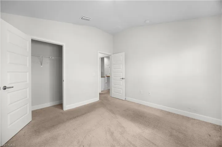 Unfurnished bedroom featuring carpet flooring, lofted ceiling, and a closet