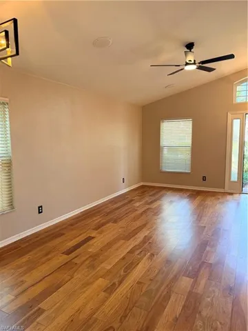 Great room featuring plenty of natural light, hardwood wood floors, a ceiling fan, and vaulted ceiling