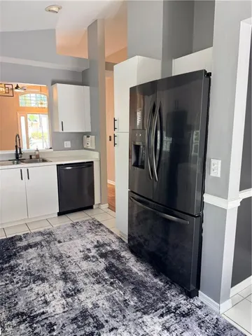 Kitchen featuring white cabinets, black appliances &  tile  floors,