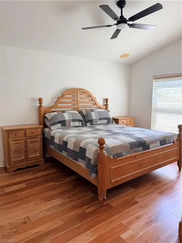 Bedroom with  wood floors, a ceiling fan, and vaulted ceiling and view of  private backyard