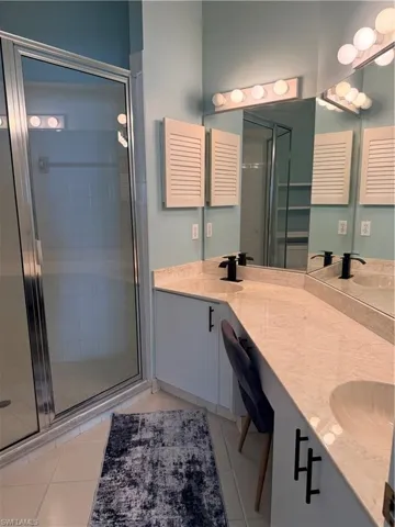 Primary Full bath with double vanity, a stall shower, and light tile patterned floors
