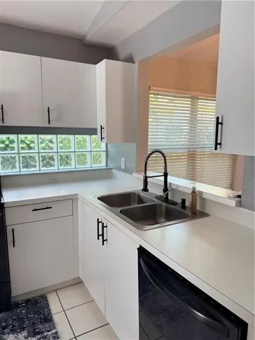 Kitchen with white cabinetry, white dishwasher, light countertops, and tile floor