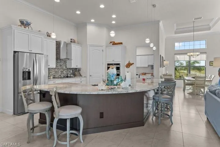 Kitchen with appliances with stainless steel finishes, white cabinetry, hanging light fixtures, and a large island