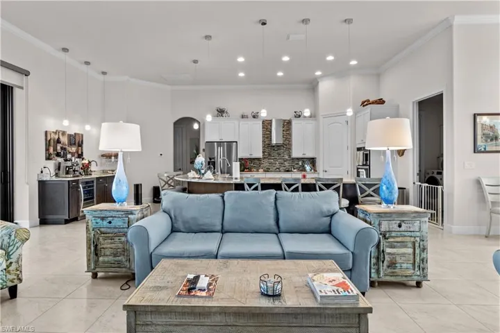 Living room featuring wine cooler, light tile patterned flooring, and ornamental molding