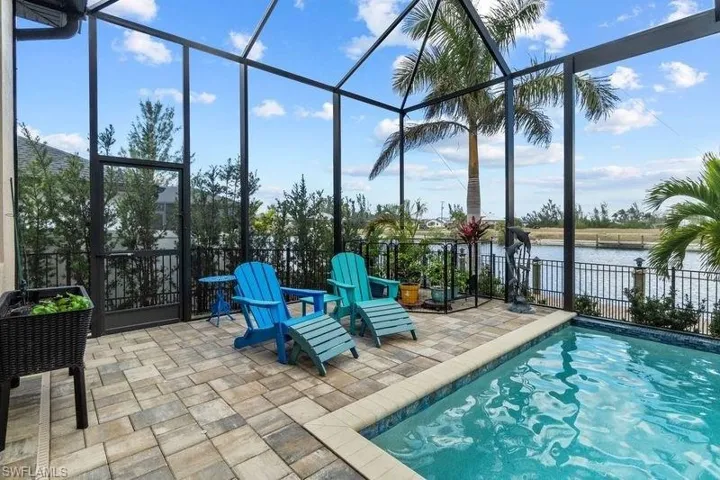 View of swimming pool with glass enclosure, a water view, and a patio