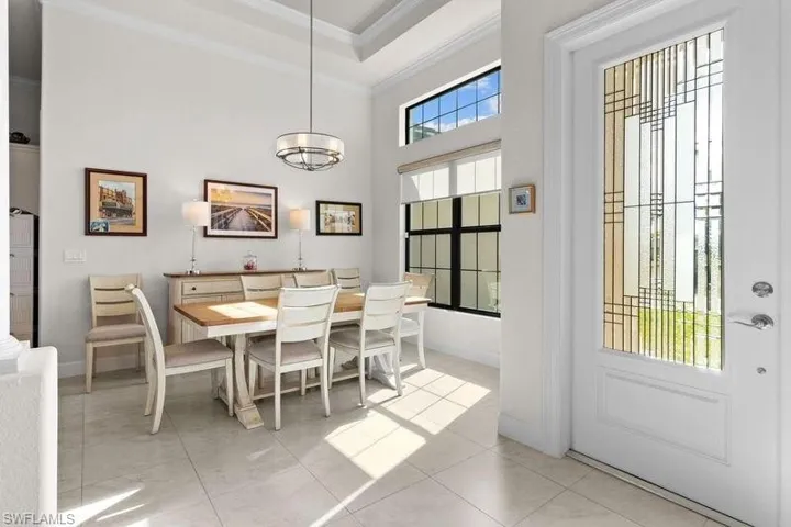 Tiled dining area with a high ceiling and ornamental molding
