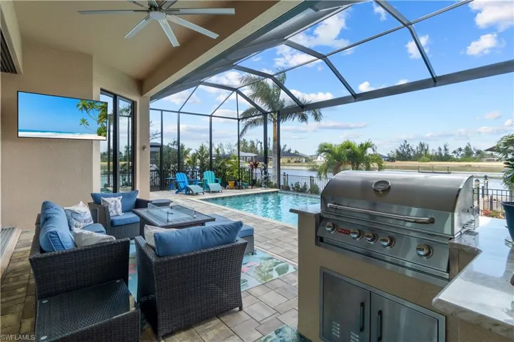 View of patio with an outdoor kitchen, an outdoor hangout area, area for grilling, a lanai, and a water view