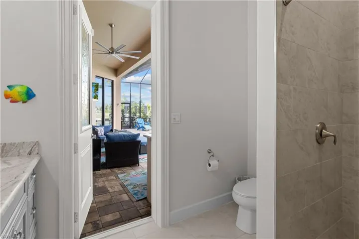Bathroom featuring a tile shower, vanity, toilet, and ceiling fan