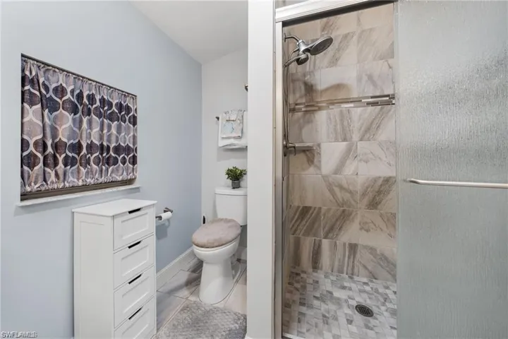 Walk-in shower featuring tiled walls and a mosaic floor