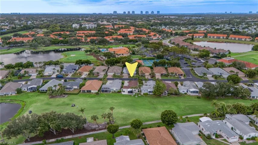 Aerial perspective of a neighborhood with residential properties, golf course, and multiple water features