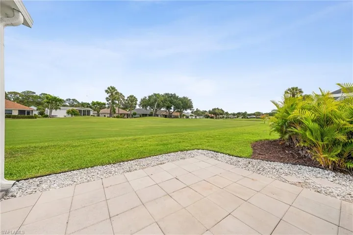Expansive outdoor patio with paver flooring, bordered by decorative gravel and lush landscaping