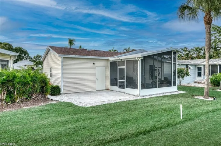 Expansive green lawn featuring a screened-in patio, white siding exterior, and an additional paver patio