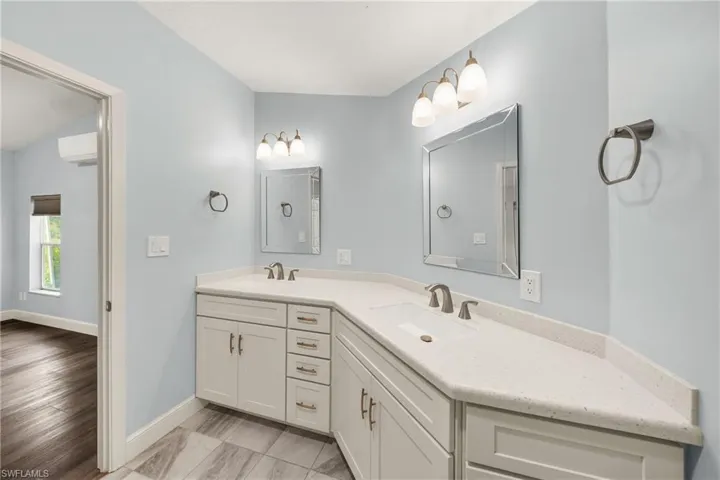 Bathroom featuring a dual vanity with white cabinetry, light-colored countertops, undermount sinks, and brushed nickel hardware