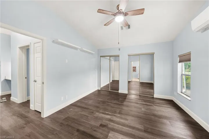 Spacious room featuring dark wood-finish flooring, light blue walls, and white trim