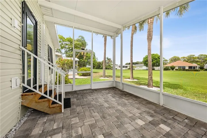 Screened lanai featuring a paver flooring, exterior siding, and a partial staircase