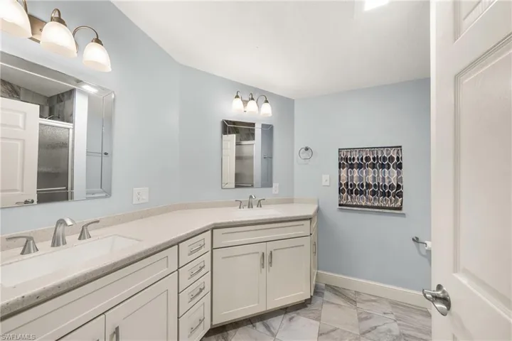 Double vanity with integrated sinks, light-toned countertops, and brushed nickel fixtures