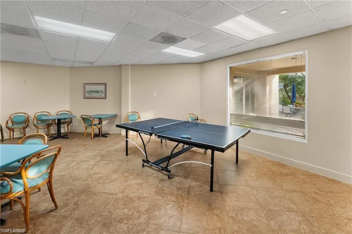 Recreation room featuring a window overlooking an outdoor patio, recessed lighting, and tile flooring