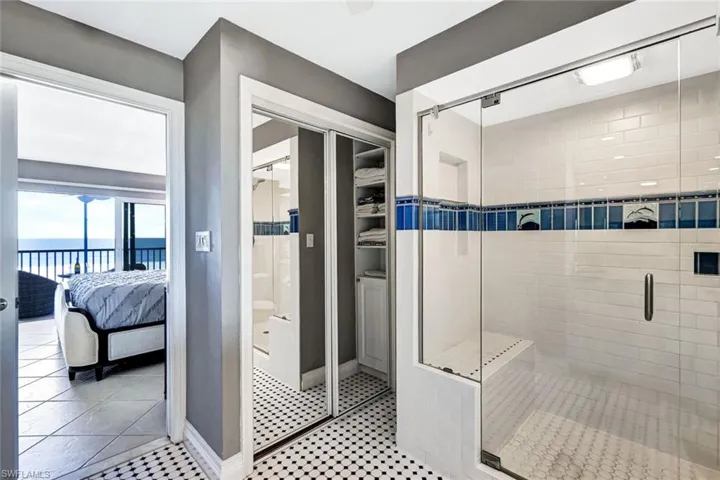 Bathroom with connected bathroom, a shower stall, tile patterned flooring, and a water view