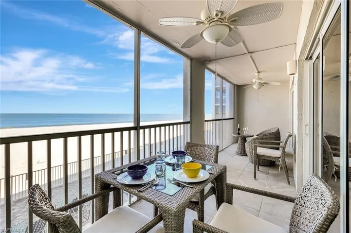 Sunroom / solarium featuring ceiling fan, a balcony, view of water and beach, and outdoor dining area
