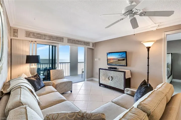 Tiled living room with a textured ceiling, crown molding, and ceiling fan