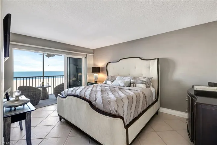 Bedroom featuring a water view, light tile patterned floors, a textured ceiling, and access to exterior