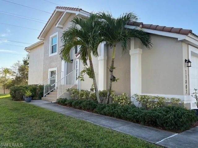 View of side of home featuring a tile roof, stucco siding, a lawn, and a garage