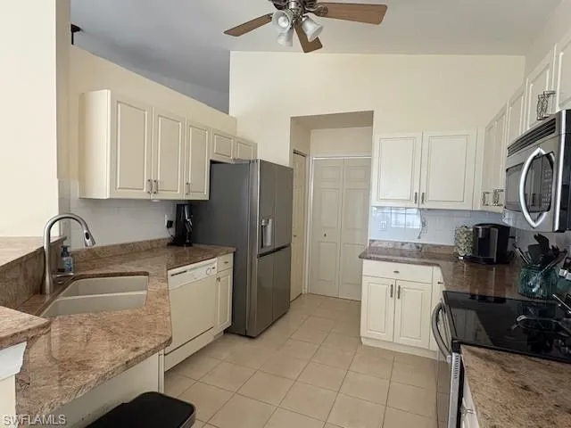 Kitchen featuring stainless steel appliances, tasteful backsplash, light tile patterned floors, light stone countertops, and a ceiling fan