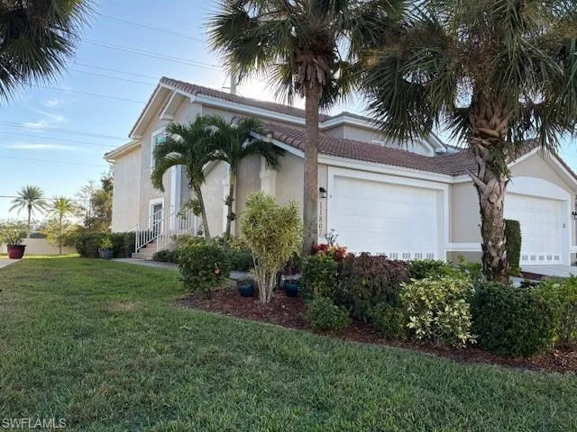 View of front of home featuring stucco siding, a front lawn, a garage, and a tiled roof