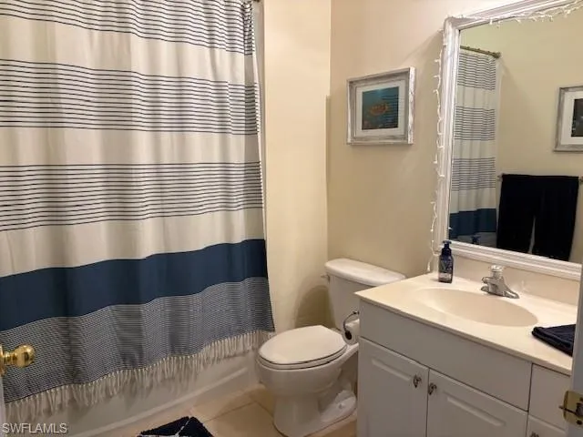 Full bath featuring vanity, light tile patterned floors, and shower / bath combo with shower curtain