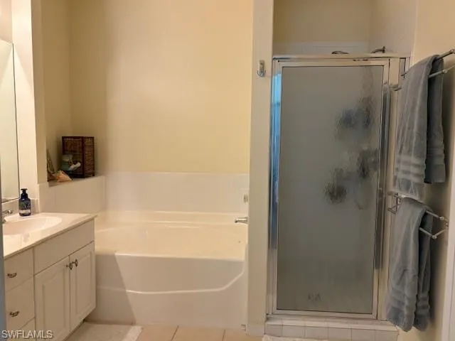 Bathroom with vanity, light tile patterned flooring, a garden tub, and a shower stall