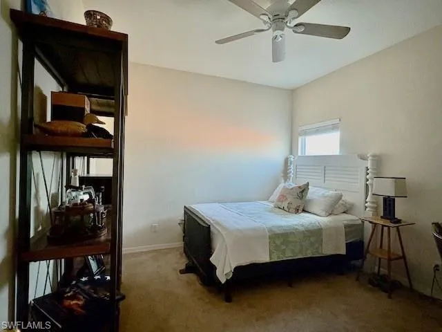 Carpeted bedroom featuring a ceiling fan and baseboards