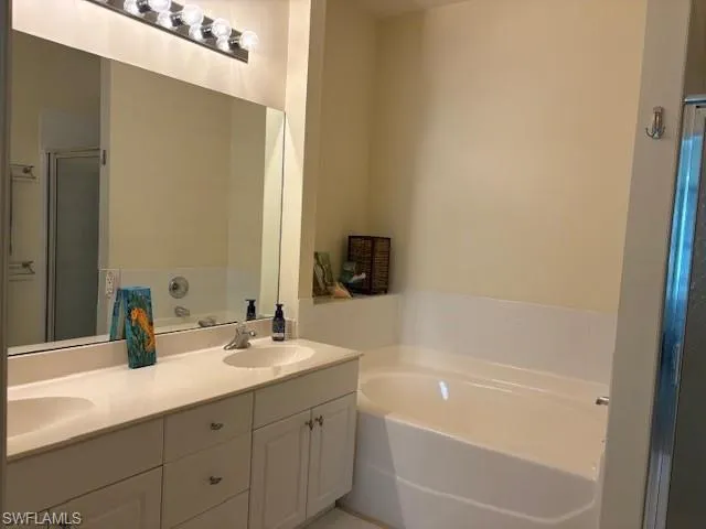 Bathroom featuring a garden tub, a stall shower, and double vanity
