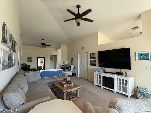 Living area with a ceiling fan, carpet, and lofted ceiling