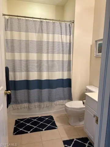 Full bath featuring vanity, light tile patterned floors, and shower / bath combo with shower curtain