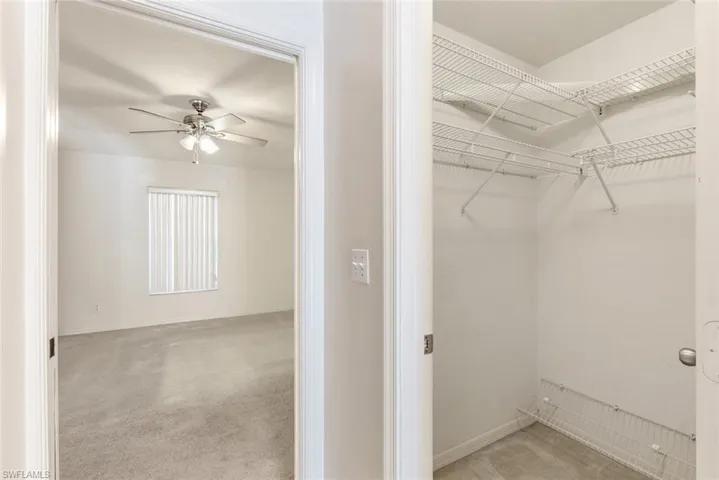 Spacious closet featuring ceiling fan and light colored carpet