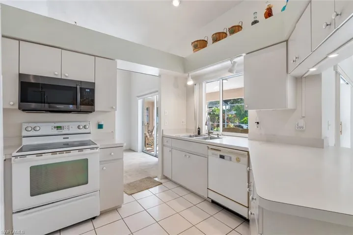 Kitchen with light colored carpet, sink, white cabinetry, and white appliances