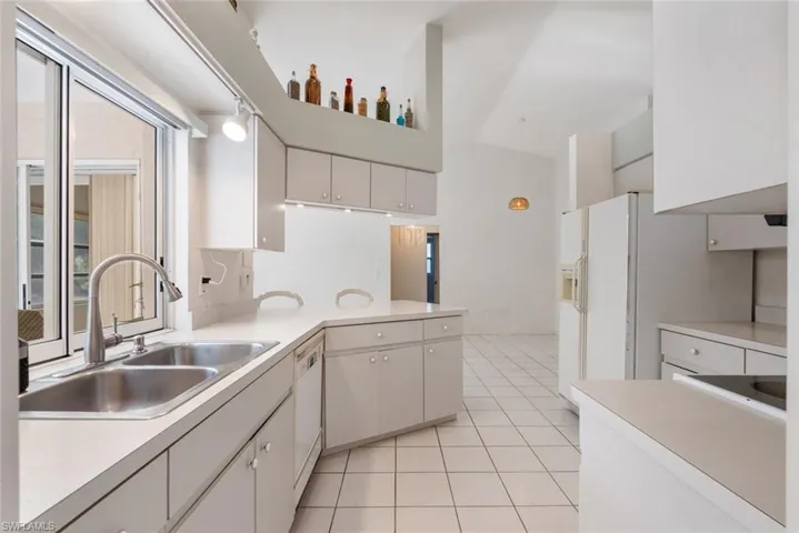 Kitchen featuring a healthy amount of sunlight, white cabinetry, sink, and light tile flooring