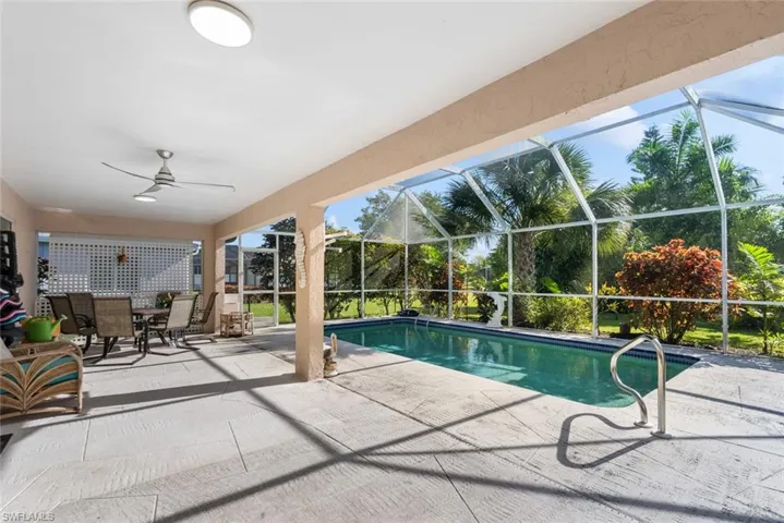 View of pool featuring a patio, glass enclosure, and ceiling fan