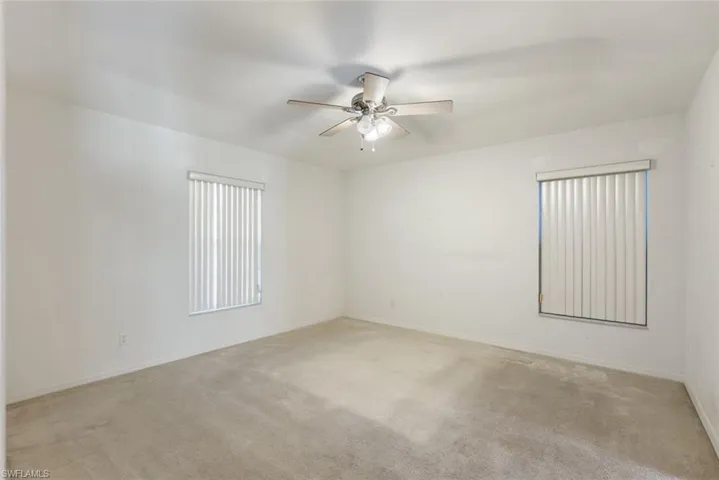 Carpeted empty room featuring ceiling fan