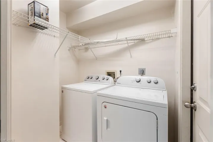 Clothes washing area featuring hookup for a washing machine, electric dryer hookup, and washing machine and clothes dryer