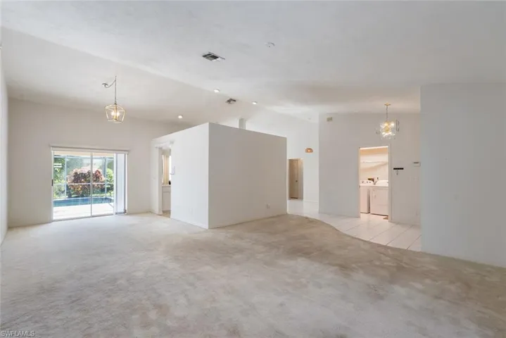 Empty room featuring a notable chandelier, washing machine and clothes dryer, and light carpet