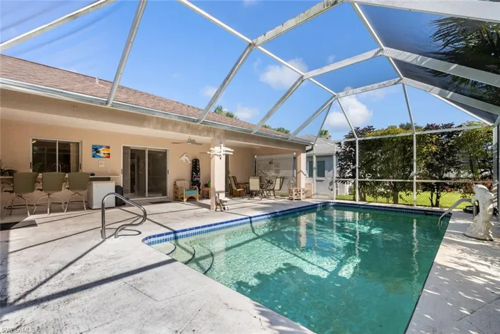 View of swimming pool featuring ceiling fan, glass enclosure, and a patio