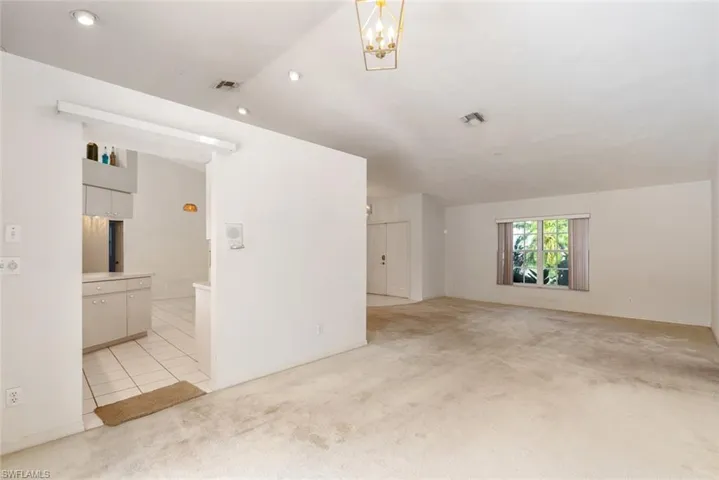Tiled spare room with a chandelier and vaulted ceiling