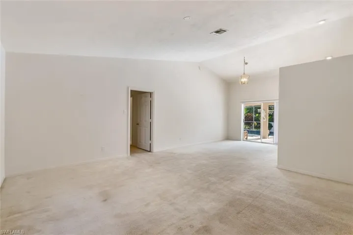 Carpeted empty room with high vaulted ceiling and french doors