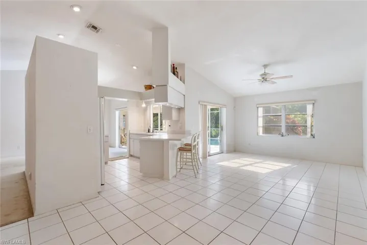 Unfurnished living room with vaulted ceiling, ceiling fan, and light tile floors