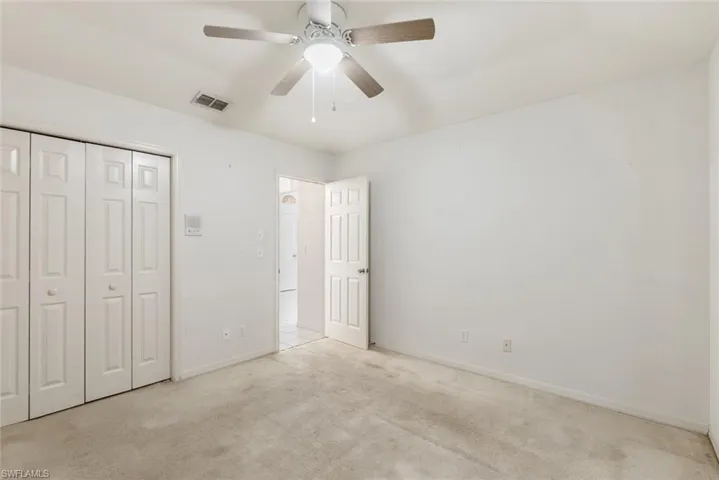 Unfurnished bedroom featuring light carpet, a closet, and ceiling fan